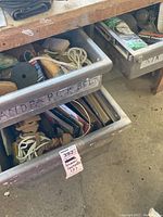 Metal bins labeled 'Sandpaper Belts' holding assorted sanding belts, polishing wheels, and sanding sponges with visible labels and cords.