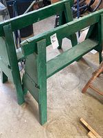Photo showing two green wooden saw horses side by side, depicting overall structure and condition.