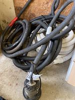 RONA submersible sump pump attached to assorted black and white flexible drainage hoses coiled on the ground.