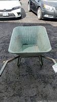 Front view of green wheelbarrow with plastic bucket and metal handles.