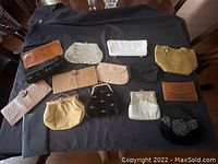 Overview of all 12 antique purses on black cloth showing variety of materials and styles.