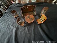 Wooden miniature antique furniture including a sofa, round pedestal table and four chairs displayed on black surface.
