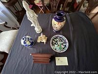 Photo showing all five Asian decorative items on black cloth including figurines, ginger jar, vase, plate and stand