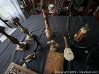 Wide view of the lot on a table: candle holders, carved figurines, wooden cross, instrument, and carved panel