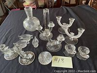 Clear crystal set shown from above including candle holders, creamer, sugar bowl, and two vases on black cloth background.
