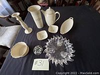 Photo showing Lenox white ceramic vases, candle holders, dishes, plates and tea pot arranged on black cloth including unique crystal candle holder
