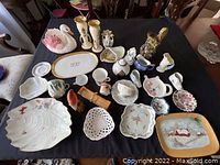 Overview of entire porcelain lot showing arranged items on table including swan figurine, vases, plates, tea cup, and other items