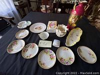 Full view of all antique porcelain plates, vases, and trinket box displayed on black table