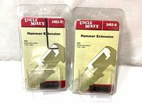 Front view of two Uncle Mike's 2452-0 Hammer Extensions in open blister packaging with red and white labels. Shows product name, model number, and compatibility with Marlin Lever Actions (1967-1982).