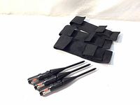 Three black Bushnell laser bore sighters next to black fabric carrying cases on a white surface