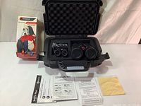 Two sets of Simmons Prosport binoculars in a protective foam-lined black hard case with manuals and cleaning cloth on the table next to the open case and original shipping box.