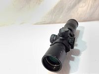 Side and front angled views of the Excalibur Tact 100 black crossbow scope showing the multi-coated lens, adjustment knobs, and overall body.