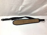 Front view of a brown suede padded hunting sling with black adjustable nylon strap and quick release clip.