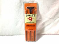 Photo showing full packaged Hoppe's 3-piece cleaning rod in orange and cream plastic packaging, visible rod sections inside.