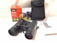 Product box, carrying case, binoculars, manual and cloth shown together on white background.