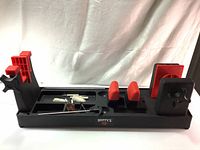 Front angle showing the Hoppe's vise with red and black locking supports and cleaning brushes in the tray.