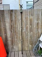 Full view of the Primos Monopod Trigger Stick GEN3 showing entire adjustable length against a wooden fence background.