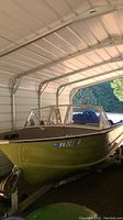 Front-quarter view of green aluminum V-hull boat under metal carport
