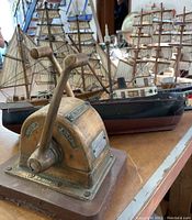 Front view of Morse brass marine engine control lever with wooden base and model ships in background