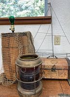 Full view of brass ship lantern, wire sailboat, fishing net, and decorative chest arranged on wooden surface