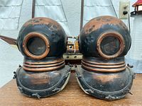 Close-up of pair of diving helmet bookends with weathered copper and black patina finish
