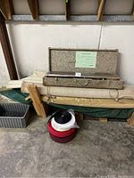 Power stretcher toolset in metal case on top of stacked upholstery rolls and wrapped materials