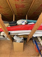 View of stacked rolls of fabric including red netting, Naugahyde, vinyl, polyester rolls, and Velcro strips.