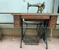 Full view of sewing machine installed in wooden table with treadle base