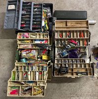 Top-down view of five open tackle boxes filled with assorted fishing lures, weights, lines, and accessories.