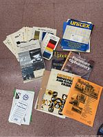 Various upholstery catalogs, brochures, and fabric/thread sample boards spread on floor
