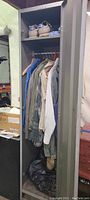 Open locker showing men's jackets and shirts hanging, shoes on top shelf, and some floor items.