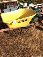 Yellow Stanley plastic wheelbarrow with metal frame, side view showing label