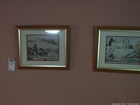 Two framed art prints side by side on a wall with visible tags
