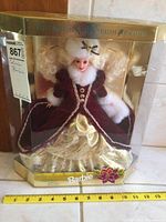 Full front view of Holiday Barbie doll in packaging showing full attire, packaging details and measurement scale for size reference.