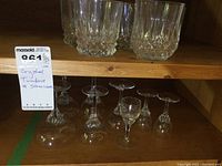 Multiple crystal tumblers and stemware arranged on wooden shelving, showing variety and cut details.