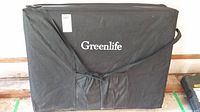 Full view of the Greenlife branded black fabric carrying bag containing the folded massage table, with shoulder strap visible.