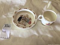 Photo of the child's ceramic bowl and mug on a fabric background showing the bunny illustrations.