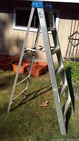 Full view of the aluminum step ladder showing the overall condition and structure outdoors.