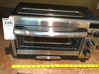 Front view of Hamilton Beach stainless steel toaster oven placed on countertop with measuring tape in front.