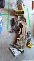 Lot contents showing toolbelt, claw hammer, pry bar, screwdrivers, measuring tapes, and carpenter's square on concrete floor.