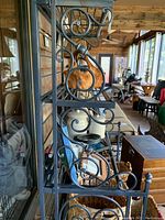 Side angle showing the metal scrollwork design on the rack and lower shelves with various household items on them.