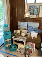 Wide view of the lot includes cabinet, shelving unit, storage baskets, clock, prints, glassware, towels, and decorative items