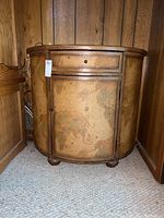 Front angle showing the chest with a drawer and cabinet door, the world map design and leather trim clearly visible. Scratch marks on surface can be seen.