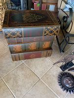 Front view of chest showing four drawers designed with book spine patterns and decorative gold accents.