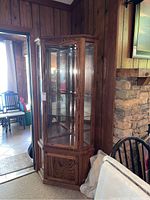Front view of the corner curio cabinet showing glass doors and mirrored back inside.