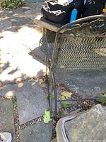 Full view of the metal glider bench showing decorative backrest, mesh seat and side frame with some rust on metal surface.
