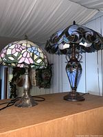 Overview of both lamps side by side on wooden surface under draped ceiling