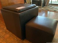 Photo showing two black vinyl-covered square stools, the larger one can be opened for storage.