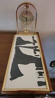 Photo showing the mantel clock and the framed abstract wall art on a wooden surface