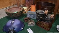 Full view of garden themed lot showing wire planter, bug piggy bank, resin shoe with bunnies, metal bin painted like copper, galvanized planter, metal waterer and small cast iron key box.